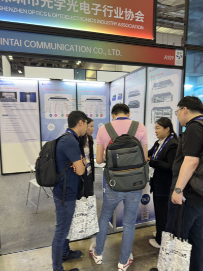 Attendees gathered at the Sintai Communication Co., Ltd. trade show booth, talking with staff and examining product displays- 02. Attendees gathered at the Sintai Communication Co., Ltd. trade show booth, talking with staff and examining product displays- 02.